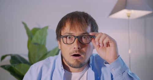 Man Adjusts Glasses in Shock and Surprise