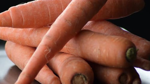 Raw Carrots Gyrating on a Black Tray