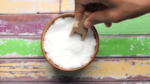 Scooping Sugar from Bowl with Wooden Utensil