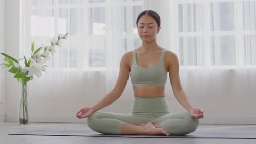 Woman Meditating on Yoga Mat in Bright Room