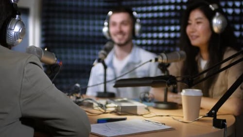 Male Radio Host Chatting with Guests in Studio