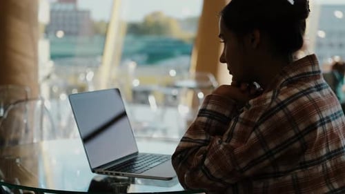 Young Adult Working on Laptop in Urban Cafe