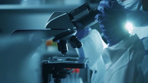 Scientist Using Microscope in Dark Laboratory