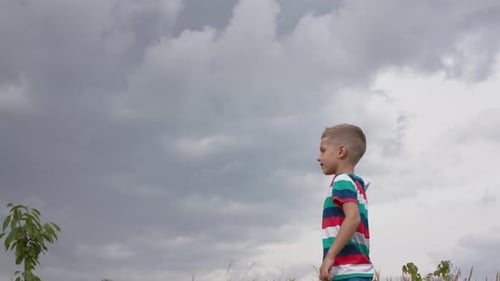 Happy Little Boy Playing With A Paper Airplane In A Field.