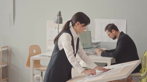 Female Asian Engineer Drawing Blueprint in Office