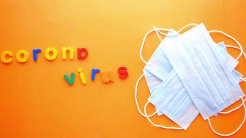 Close Up of Blue Surgical Masks and Colorful Plastic Alphabet on Orange