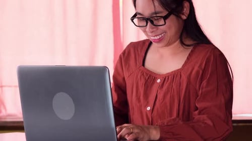 Woman Smiling While Using Computer in Home