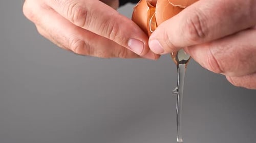 Hands Crack a Brown Egg and Pour it Out