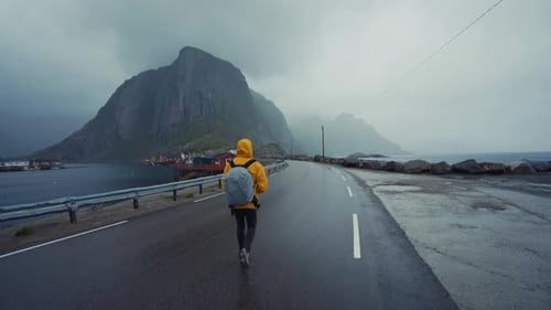 Tourist with backpack walking on misty remote road