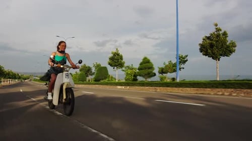 Modèle à la mode caucasien insouciant qui sort la langue et sourit en conduisant un cyclomoteur blanc