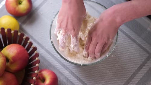 Hands Mixing Dough in Bowl with Apples