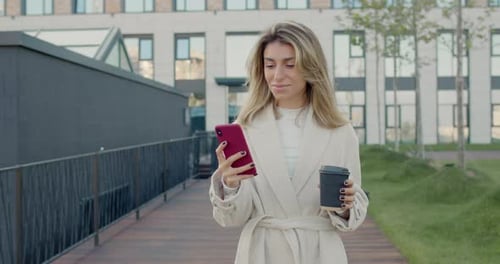 Crop View of Businesswoman with Blond Hair Using Smartphone and Holding Paper Coffee Cup. Successful