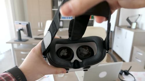 Hands Holding Virtual Reality Goggles in Office