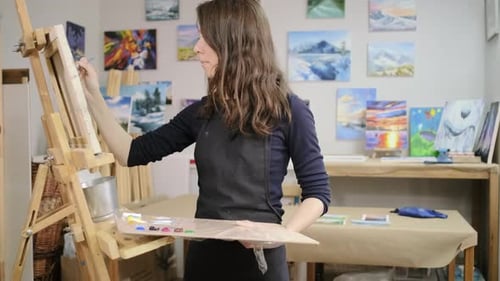 Mujer joven está aprendiendo a dibujar en un taller artístico de pintura sobre lienzo