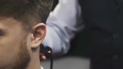 Nahaufnahme eines Mannes, der sich von einem professionellen Friseur die Haare rasieren lässt