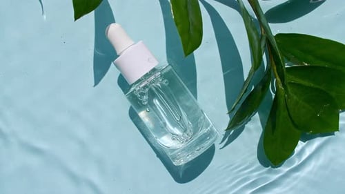Bottle of serum and a green leafy plant