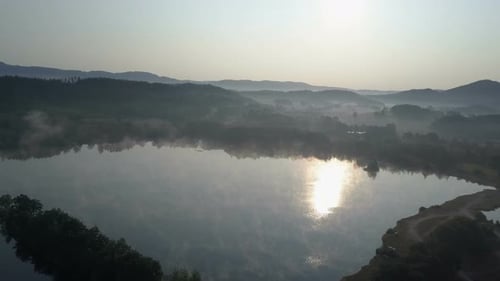 Cinematic Aerial Fly Through a Morning Fog Over a Mountain Lake. Foggy Sunrise In Mountains
