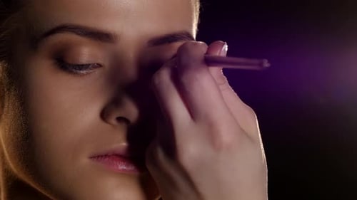 Makeup auf das weibliche Gesicht auftragen. Professionelles Makeup. Schwarz. Nahaufnahme