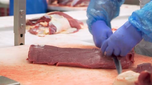 Person Cuts Pieces of Beef With Knife