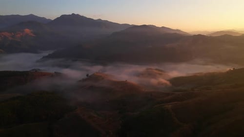 4K aerial view over a misty mountainous area. The great golden sun in the morning