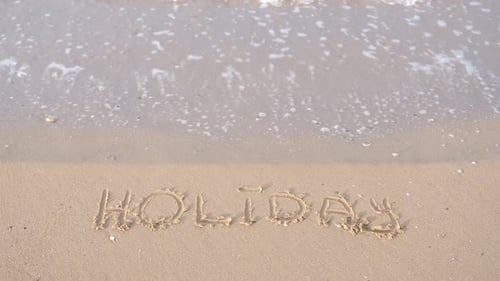 Holiday Lettering Holiday Lettering on Sand Among Waves Crashing on Beach