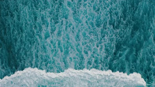 Aerial View Ocean Waves Break Into Foam Along the Shore