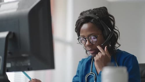 Female Medical Professional Working at Computer with Headset