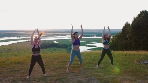 Women Exercising Outdoors by River at Sunset
