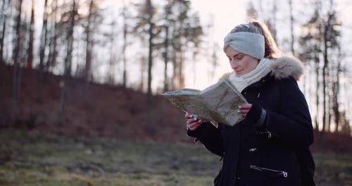 Woman Reads Map in Golden Forest