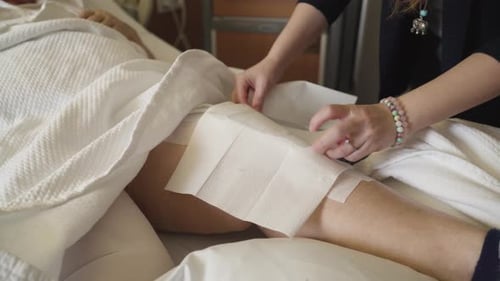 Appliquer une pression de glace sur le genou nouvellement opéré d'une vieille dame.