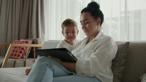 Mother and Child Using Tablet on Couch Together