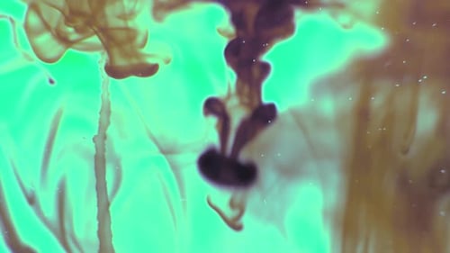Smokey green and red ink drops being dripped into water and swirling around MACRO