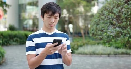 Young Adult Using Smartphone in City Park