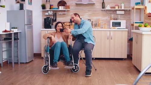 Couple Watching Phone Together in Bright Kitchen