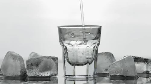 Clear Liquid Being Poured into Glass with Ice