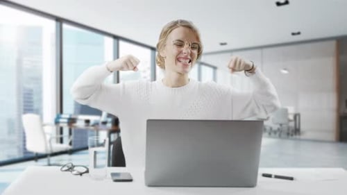Excited Businesswoman Is Winning While Sitting at the Office. The Woman Sit at Desk Feel Euphoric