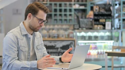 Man on Video Call at Cafe Using Laptop