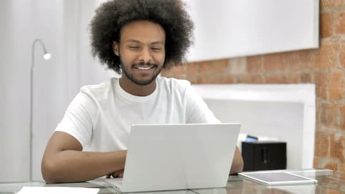 Man Smiling at Laptop in Home Office