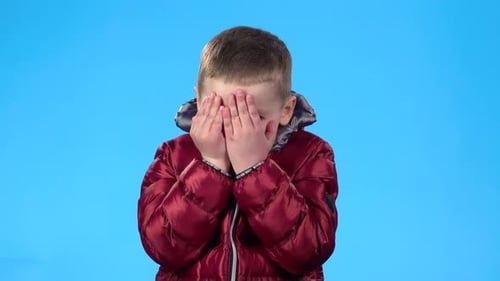 Niño actuando como asustado, escondiéndose, cerrando su rostro con las manos