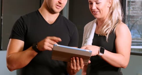 Man and Woman Using Tablet in Gym Setting