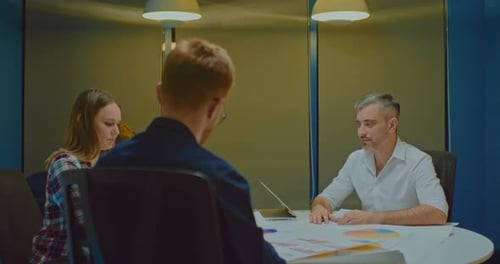 Grayhaired Male Director at a Meeting with Business Partners in a Modern Coworking Office Discussing
