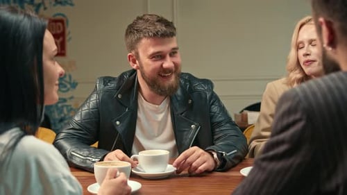 Handsome stylish guy drinks filter coffee in a coffee shop in the company of cheerful friends.