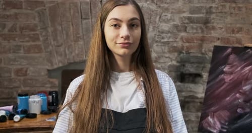 Portrait of Talented Innovative Pretty Female Artist with Brush and Her Canvas on Background