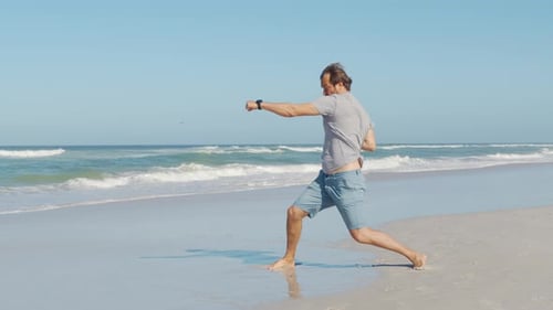 Cheerful and Happy Young Man Actively Dancing While Walking Down the Ocean