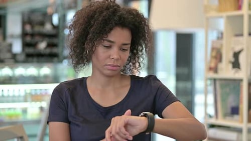 Woman Checking Smartwatch in Cafe Setting