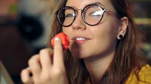 Young Woman Smiling Eating a Red Macaron