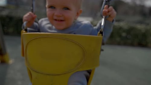 Cheerful Boy Rides Swings at Playground for Children