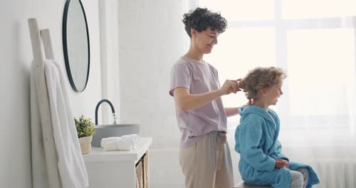 Woman Brushing Child's Hair in Bright Bathroom