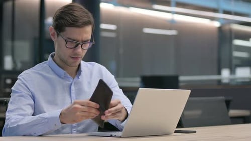 Junger Mann checkt leere Brieftasche im Büro