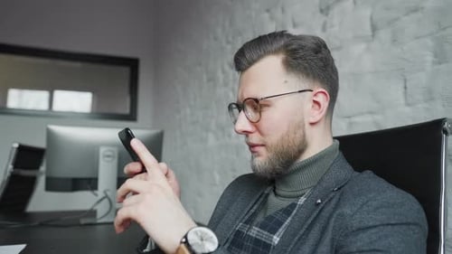 Man in Office Using Phone at Desk